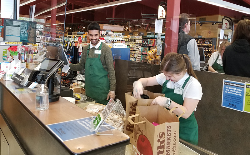 Jacob Rider and Ellie Bright help customers at Silverton’s Roth’s Fresh Market. Recently installed Plexiglas shields compensate for the 6-foot distancing guideline. Brenna Wiegand