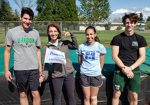 Alison Wood, second from left, is shown with her Regis high jumpers, from left, Josh Blish, Kaila Hayes and Tim Crowell. Wood holds the flag she won at the Drake Relays in April. James Day